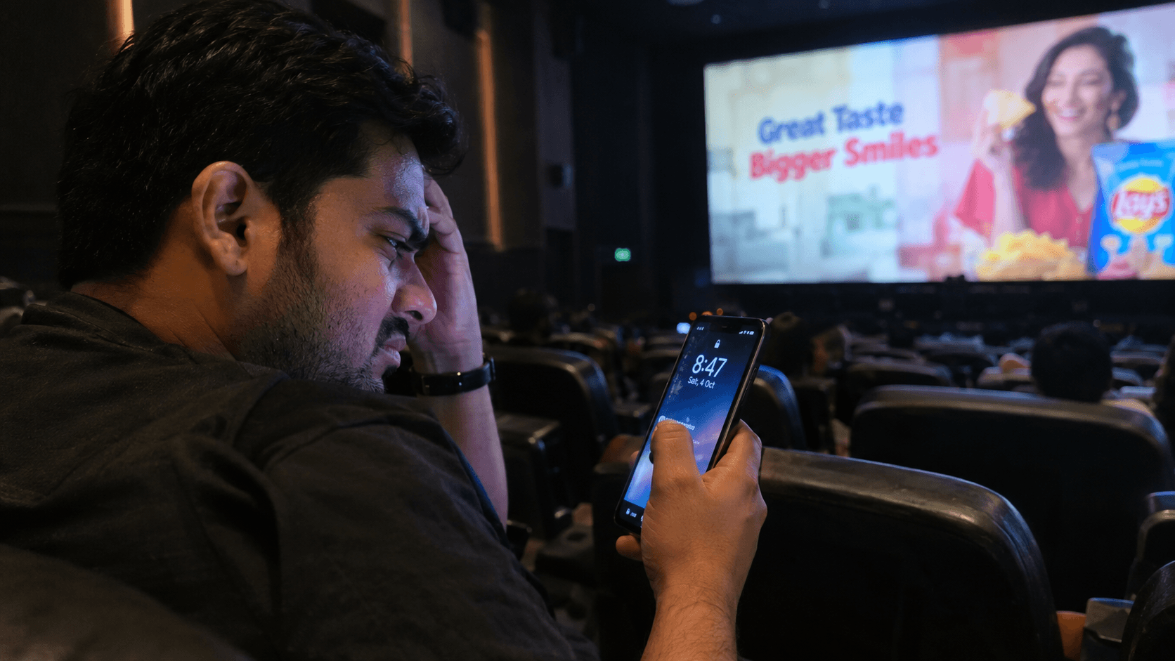 Frustrated moviegoer waiting in a cinema seat while advertisements delay the film
